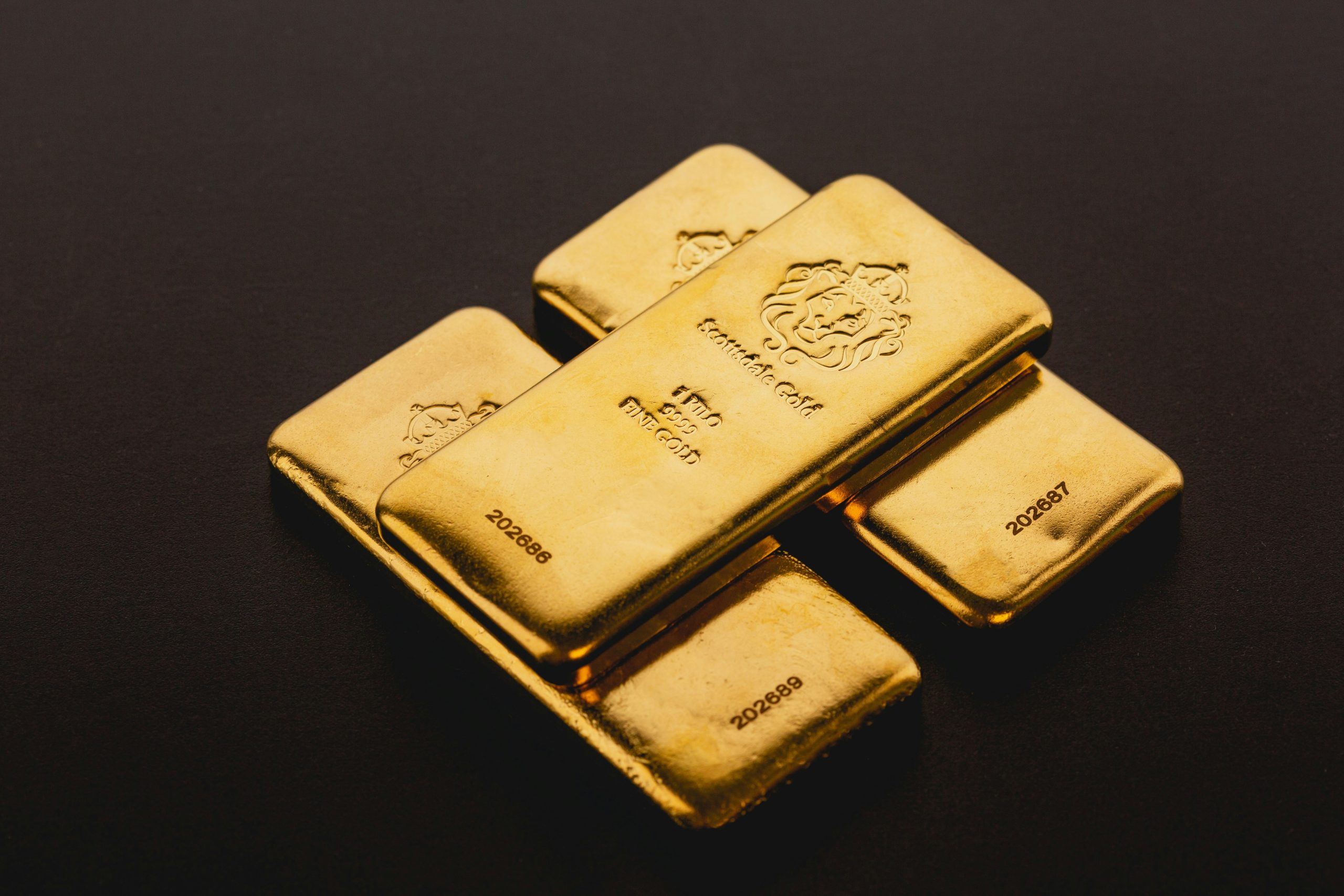 Stack of gleaming gold bars, representing the 'haven first' strategy for traders seeking to preserve capital during geopolitical uncertainties and market volatility.