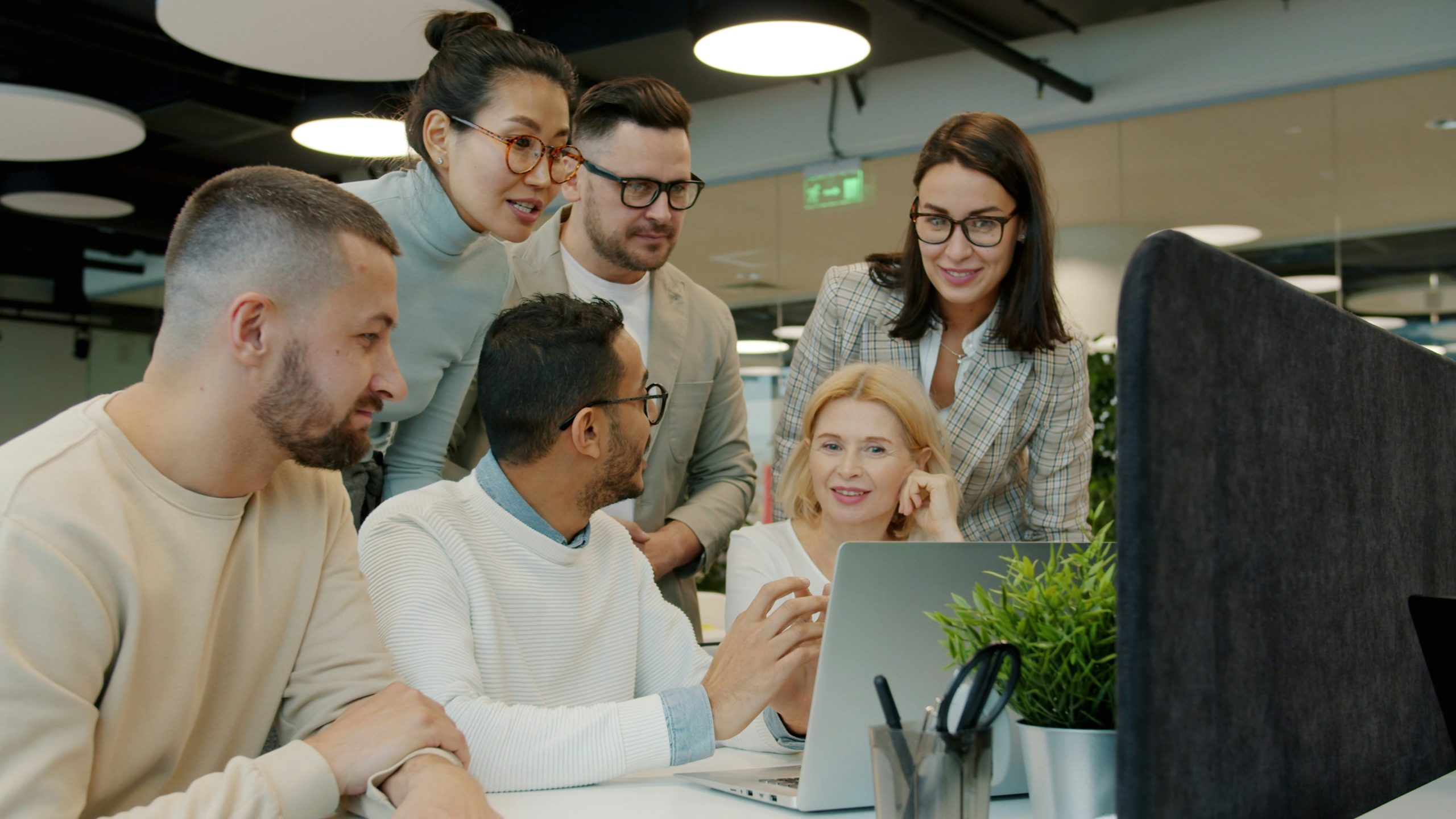 A group of professionals in a modern office collaborating around a large screen, symbolizing how AI-driven social trading platforms foster engagement and improve client retention for Introducing Brokers.
