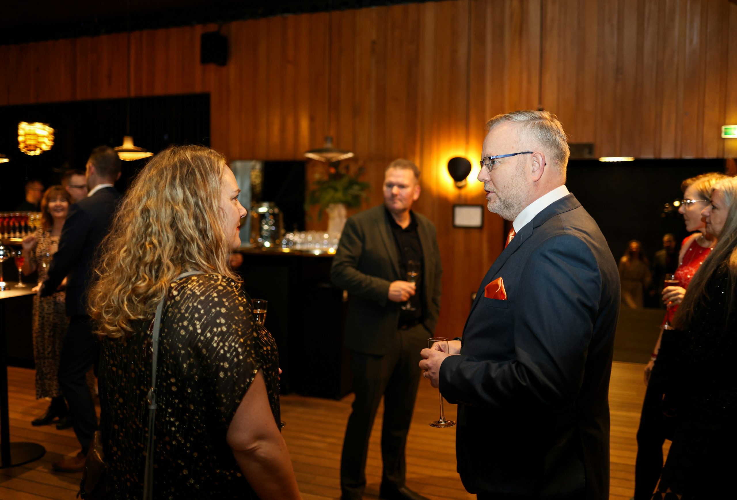 A group of diverse professionals engaging in a networking event, symbolizing the recruitment of master IBs, influencers, and educators for scaling a brokerage network.